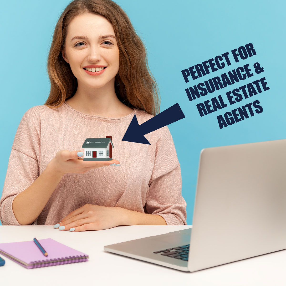 Smiling office worker at a desk holding a home-shaped stress ball with insurance company logo